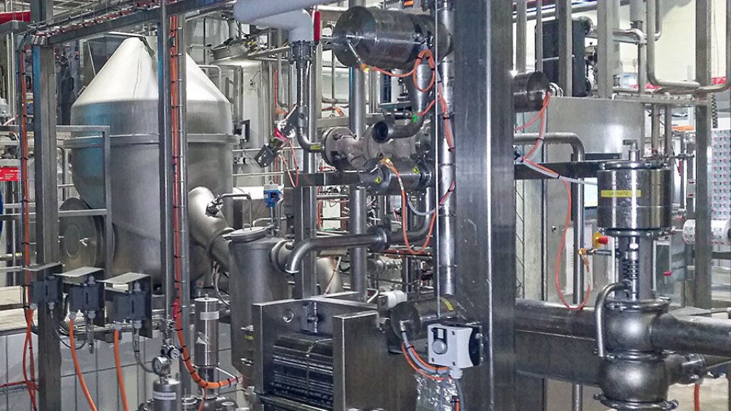 Stainless steel industrial plant with piping and vessels for the production of quark and fresh cheese.